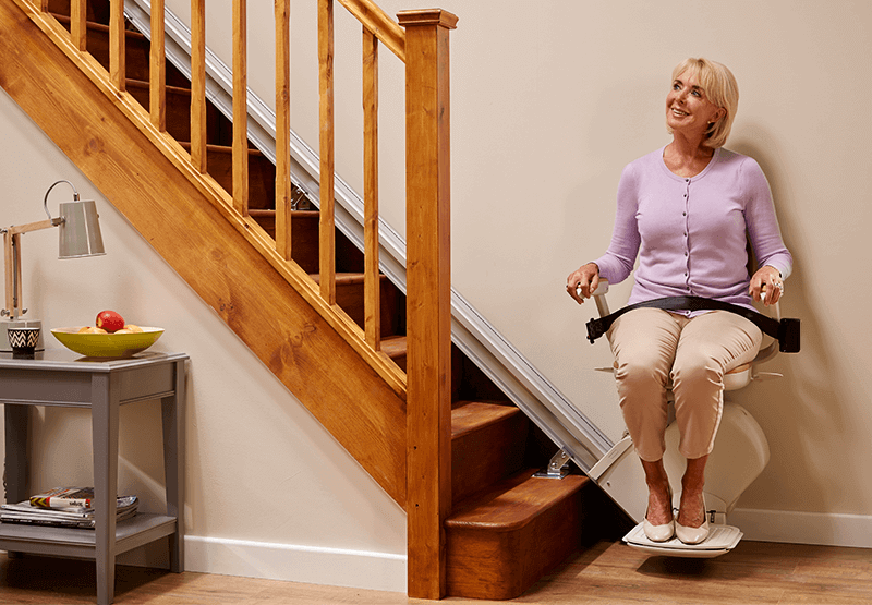 Lady sitting on a stairlift on straight staircase