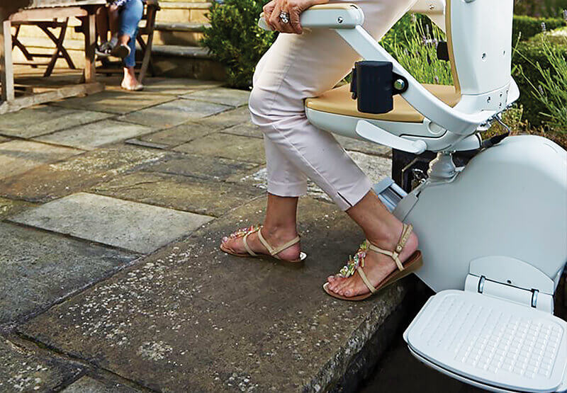 Lady stepping off an outdoor stairlift